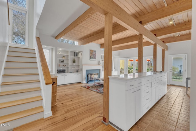206 Spring Ln, Chapel Hill, NC 27514 - kitchen featuring a wooden ceiling with exposed beams, white cabinets, open floor plan, a glass covered fireplace, and light countertops