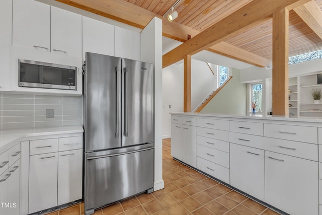 206 Spring Ln, Chapel Hill, NC 27514 - kitchen with appliances with stainless steel finishes, a wood ceiling with exposed beams, light tile patterned floors, backsplash, and white cabinets