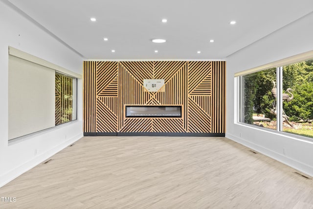 115 Ashworth Dr, Durham, NC 27707 - unfurnished living room with an accent wall, recessed lighting, a glass covered fireplace, and wood finished floors