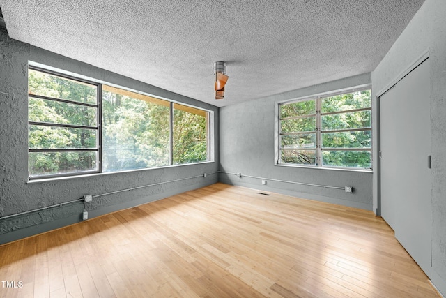 115 Ashworth Dr, Durham, NC 27707 - unfurnished room with wood finished floors, a textured ceiling, and a textured wall