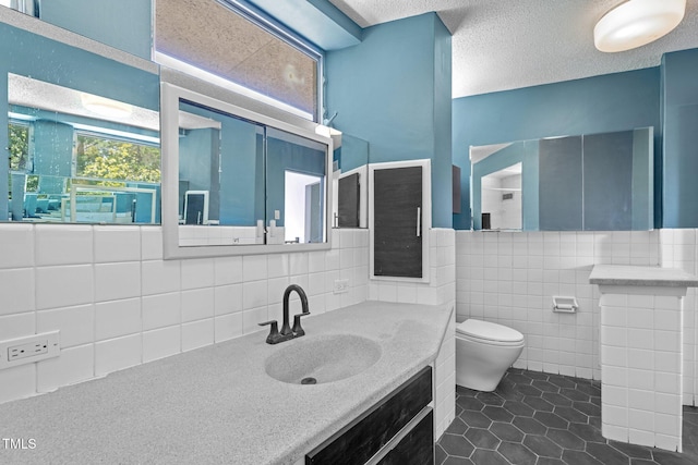 115 Ashworth Dr, Durham, NC 27707 - bathroom featuring tile patterned floors, tile walls, vanity, a textured ceiling, and wainscoting