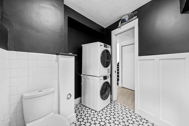 115 Ashworth Dr, Durham, NC 27707 - bathroom with stacked washer / drying machine, tile patterned floors, a textured ceiling, and wainscoting