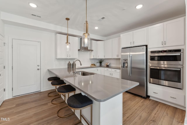 1236 S Person St Unit 101, Raleigh, NC 27601 - kitchen with appliances with stainless steel finishes, a breakfast bar area, white cabinets, wall chimney range hood, and recessed lighting