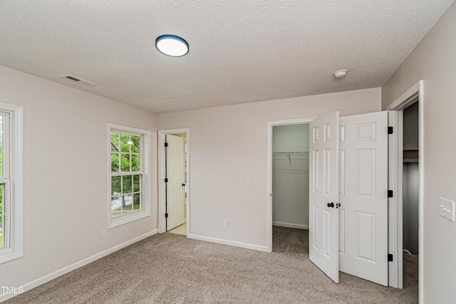 2738 Garden Knoll Ln, Raleigh, NC 27614 - unfurnished bedroom featuring a textured ceiling, light carpet, and a walk in closet