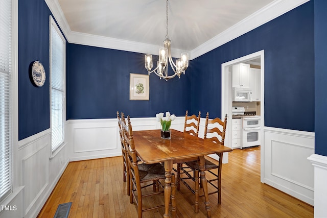102 Whitlock Ln, Cary, NC 27513 - dining room featuring a chandelier, ornamental molding, wainscoting, hardwood / wood-style floors, and a decorative wall