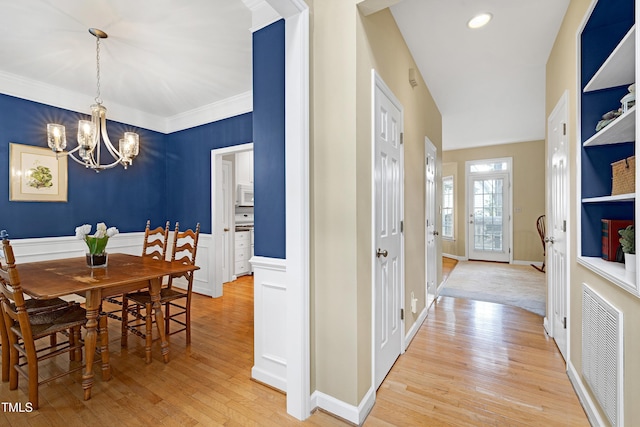 102 Whitlock Ln, Cary, NC 27513 - dining room with a chandelier, light wood-style floors, crown molding, and a wainscoted wall