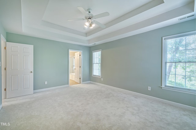 102 Whitlock Ln, Cary, NC 27513 - unfurnished bedroom featuring a raised ceiling, light colored carpet, multiple windows, and connected bathroom