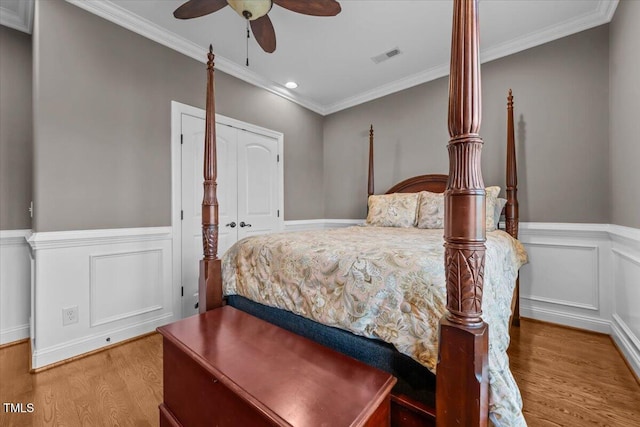 2011 Gibsonville Ossipee Rd, Elon, NC 27244 - bedroom featuring wood finished floors, a wainscoted wall, crown molding, recessed lighting, and a decorative wall