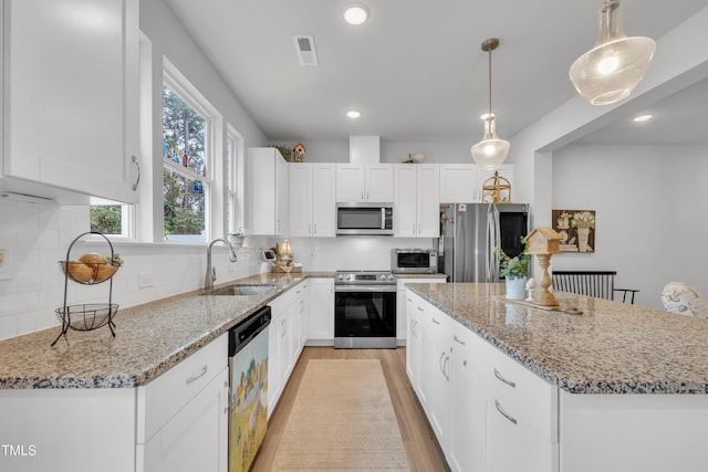 110 Gilder Woods Dr, Garner, NC 27529 - kitchen with stainless steel appliances, light wood finished floors, white cabinetry, light stone countertops, and recessed lighting