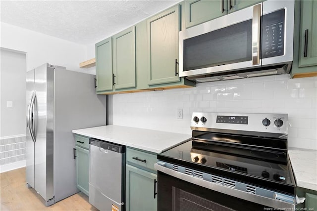 6123 Malvern Cir, Fayetteville, NC 28314 - kitchen with appliances with stainless steel finishes, green cabinets, light wood finished floors, tasteful backsplash, and a textured ceiling