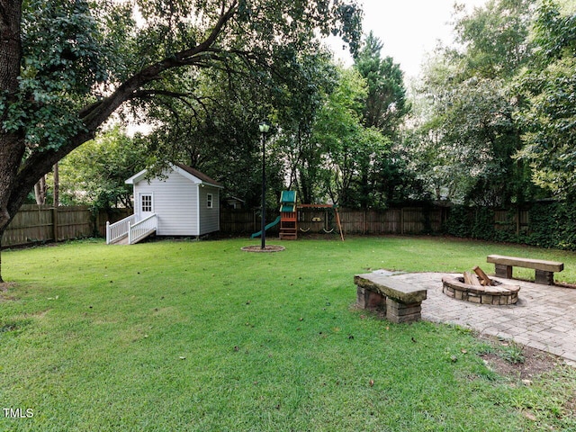 3525 Lytham Pl, Raleigh, NC 27604 - fenced backyard featuring a fire pit, a playground, an outbuilding, and a patio area