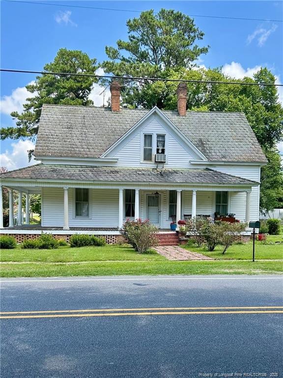 512 W Main St W, Rowland, NC 28383 - farmhouse featuring a porch, a chimney, a front yard, and roof with shingles