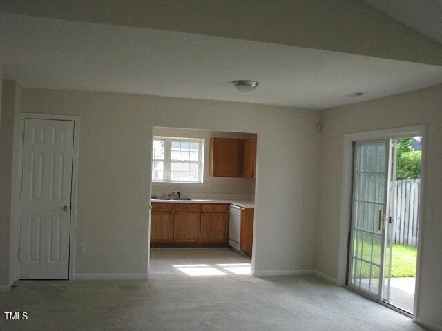 4419 Nightfall Ct, Durham, NC 27713 - kitchen with brown cabinets, light countertops, white dishwasher, and light carpet