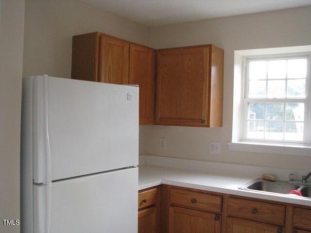 4419 Nightfall Ct, Durham, NC 27713 - kitchen featuring freestanding refrigerator, light countertops, and brown cabinets