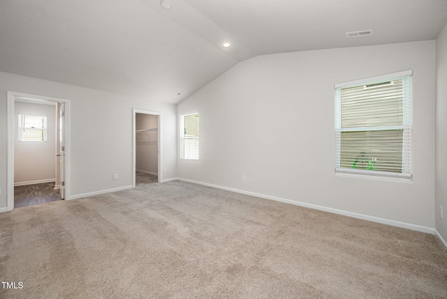 757 Frosty Way, Zebulon, NC 27597 - unfurnished bedroom featuring vaulted ceiling, a walk in closet, and carpet flooring