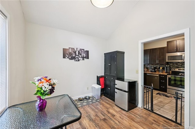 5905 Waters Edge Dr, Fayetteville, NC 28314 - kitchen featuring stainless steel appliances, lofted ceiling, dark brown cabinets, light wood-type flooring, and tasteful backsplash