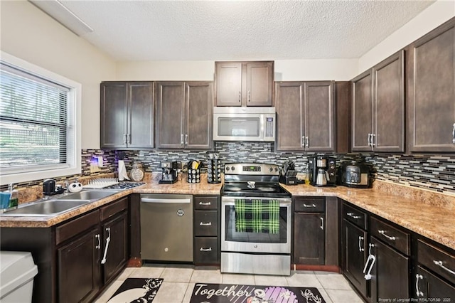 5905 Waters Edge Dr, Fayetteville, NC 28314 - kitchen with stainless steel appliances, dark brown cabinetry, light tile patterned floors, decorative backsplash, and a textured ceiling