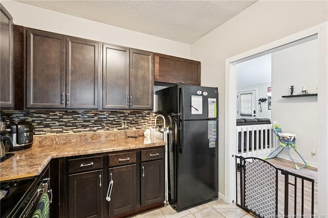 5905 Waters Edge Dr, Fayetteville, NC 28314 - kitchen featuring freestanding refrigerator, range with electric stovetop, tasteful backsplash, dark brown cabinetry, and a textured ceiling