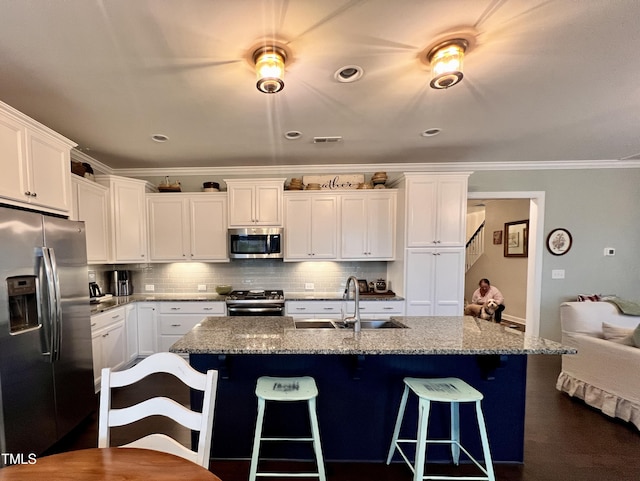 1925 Bright Kannon Way, Wendell, NC 27591 - kitchen featuring stainless steel appliances, crown molding, white cabinetry, and a kitchen breakfast bar