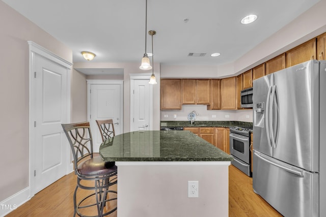 222 Glenwood Ave # 416, Raleigh, NC 27603 - kitchen featuring stainless steel appliances, brown cabinetry, light wood-style floors, a center island, and recessed lighting