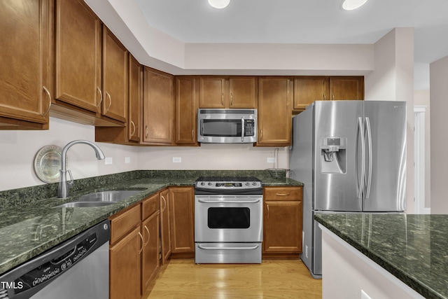 222 Glenwood Ave # 416, Raleigh, NC 27603 - kitchen with stainless steel appliances, dark stone counters, light wood-style flooring, and brown cabinets