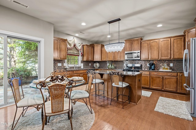 2505 Goldeneye Ct, Raleigh, NC 27606 - kitchen with brown cabinets, a kitchen island, appliances with stainless steel finishes, wood finished floors, and recessed lighting
