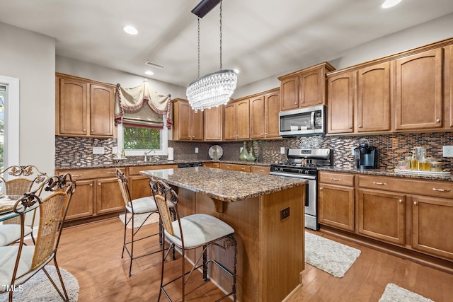 2505 Goldeneye Ct, Raleigh, NC 27606 - kitchen featuring stainless steel appliances, a kitchen island, a breakfast bar, dark stone counters, and light wood-style flooring