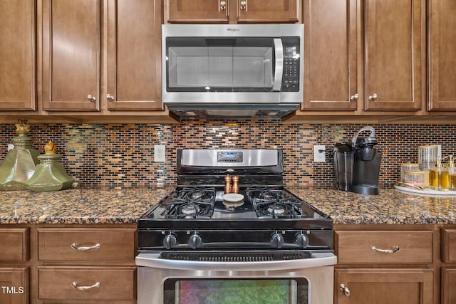 2505 Goldeneye Ct, Raleigh, NC 27606 - kitchen featuring stainless steel appliances, brown cabinetry, tasteful backsplash, and dark stone counters