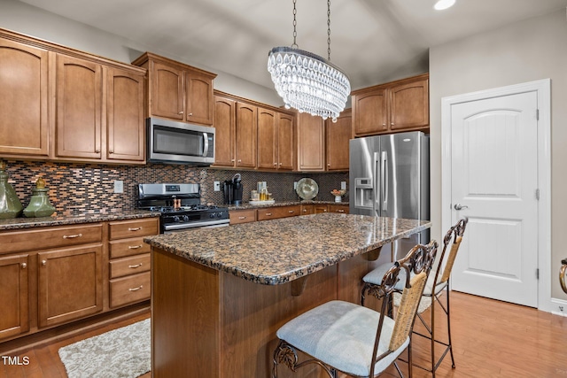 2505 Goldeneye Ct, Raleigh, NC 27606 - kitchen featuring a chandelier, stainless steel appliances, a breakfast bar, backsplash, and light wood finished floors