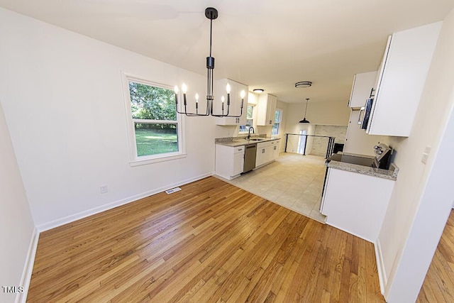 2309 Bertie Dr, Raleigh, NC 27610 - kitchen featuring light wood finished floors, a chandelier, white cabinets, and stainless steel appliances
