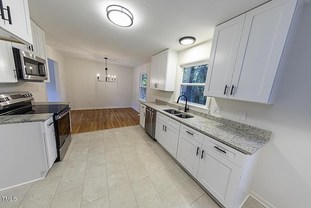 2309 Bertie Dr, Raleigh, NC 27610 - kitchen featuring appliances with stainless steel finishes, a chandelier, light stone counters, and white cabinetry