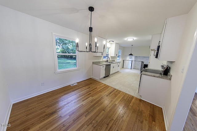 2309 Bertie Dr, Raleigh, NC 27610 - kitchen with light wood-type flooring, white cabinets, a chandelier, and appliances with stainless steel finishes