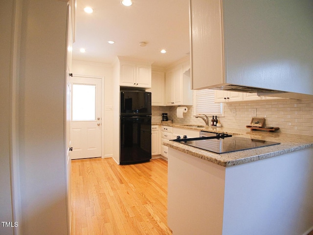 503 N Glen Dr, Raleigh, NC 27609 - kitchen with fridge, white cabinetry, light wood-style floors, decorative backsplash, and a peninsula