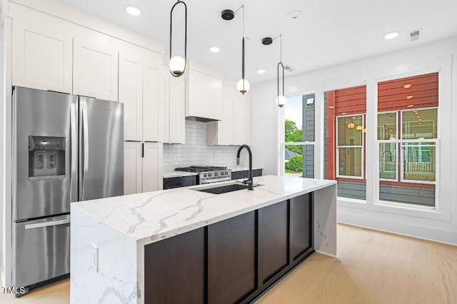 2 Seawell Ave Unit 101, Raleigh, NC 27601 - kitchen featuring stainless steel appliances, white cabinetry, tasteful backsplash, light wood-type flooring, and a center island with sink
