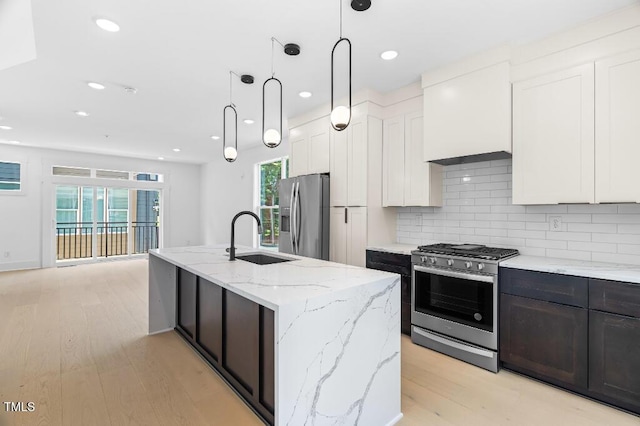2 Seawell Ave Unit 101, Raleigh, NC 27601 - kitchen featuring stainless steel appliances, light wood-type flooring, a kitchen island with sink, white cabinets, and backsplash