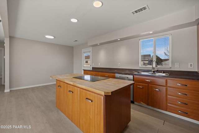 kitchen featuring dishwasher, butcher block counters, sink, a center island, and black electric stovetop