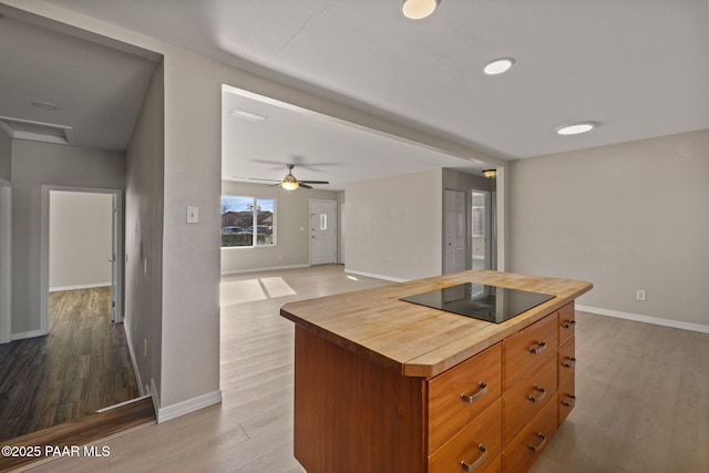 kitchen featuring wooden counters, a center island, light wood-type flooring, ceiling fan, and black electric stovetop