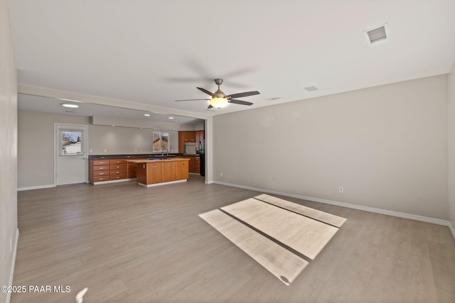 unfurnished living room with sink, light hardwood / wood-style flooring, and ceiling fan