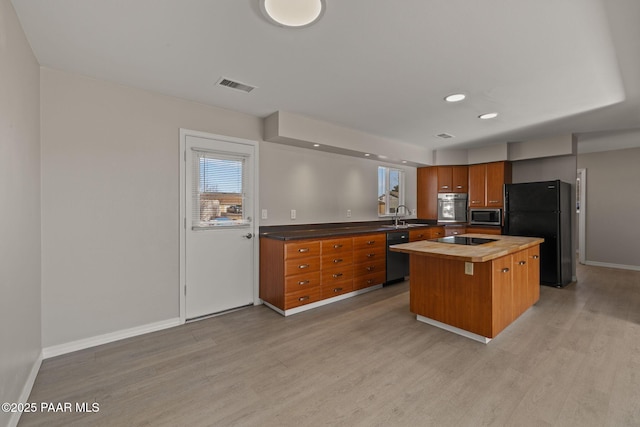 kitchen with butcher block countertops, sink, a center island, light hardwood / wood-style flooring, and black appliances