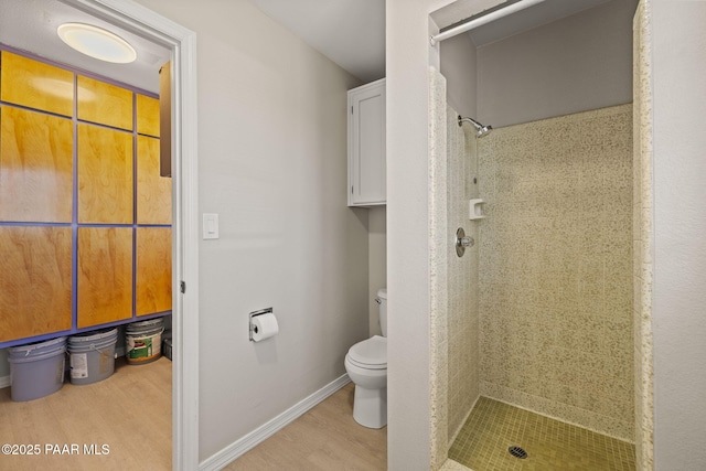 bathroom with hardwood / wood-style floors, toilet, and tiled shower