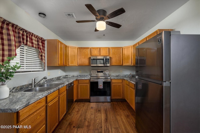 13819 S Bluebird Ln, Mayer, AZ 86333 - kitchen with appliances with stainless steel finishes, dark wood-style flooring, a ceiling fan, brown cabinetry, and dark countertops