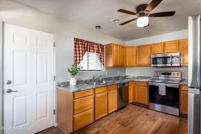 13819 S Bluebird Ln, Mayer, AZ 86333 - kitchen with appliances with stainless steel finishes, a ceiling fan, dark wood-style floors, and brown cabinets