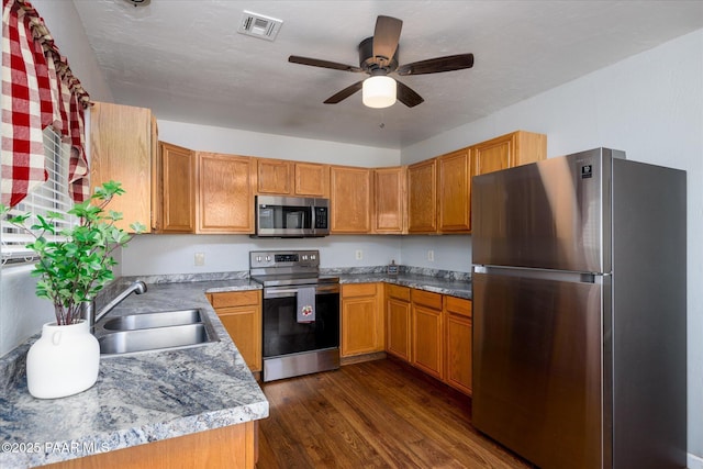 13819 S Bluebird Ln, Mayer, AZ 86333 - kitchen with appliances with stainless steel finishes, dark wood finished floors, a ceiling fan, and brown cabinets