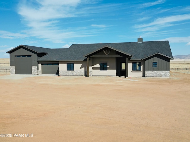 view of front of property featuring board and batten siding, stone siding, driveway, and a shingled roof