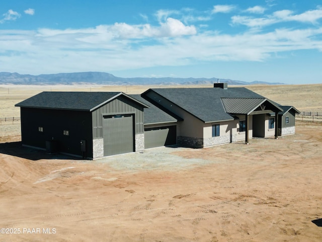 view of front of property with board and batten siding, stone siding, a mountain view, and driveway