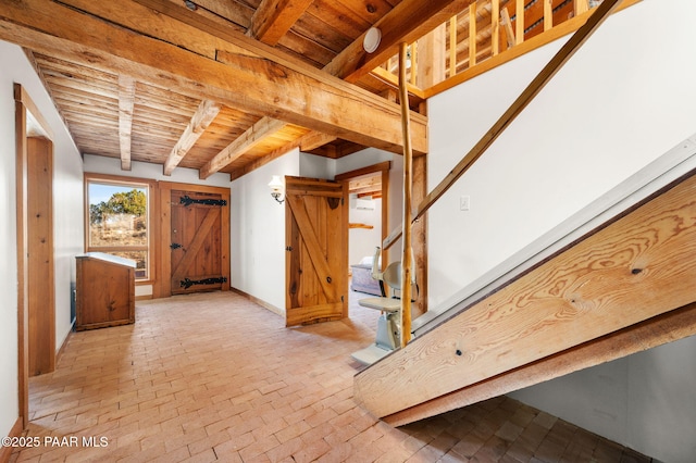 interior space with brick floor, wooden ceiling, baseboards, and beam ceiling