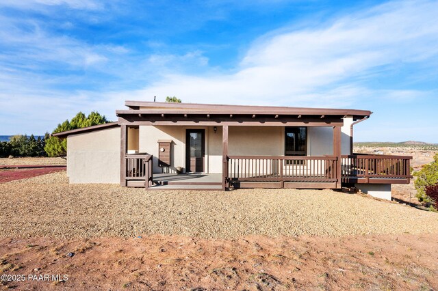 rear view of house featuring stucco siding