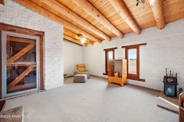 living area with a wood stove, wood ceiling, beamed ceiling, and carpet floors