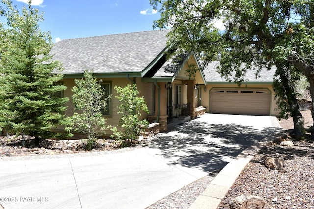 1284 Mcdonald Dr, Prescott, AZ 86303 - view of front of home featuring concrete driveway, an attached garage, a shingled roof, and stucco siding