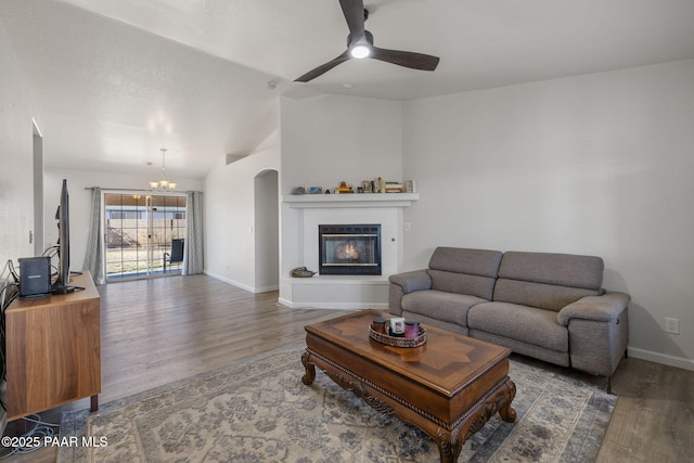 living room with vaulted ceiling, dark wood-type flooring, and ceiling fan with notable chandelier